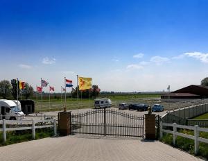 a gate with cars parked in a parking lot with flags at The Quiet Escape in Strijen