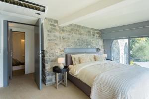 a bedroom with a bed and a stone wall at Villa Sasso On Lake Como by Rent All Como in Sala Comacina