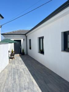 a white house with a patio with a green umbrella at Casinha da Aurora in Pedorido