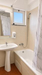 a white bathroom with a sink and a bath tub at Villa Cerro in Albufeira