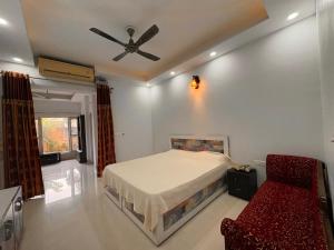 a bedroom with a bed and a ceiling fan and a chair at Golden Villas in Rewāri