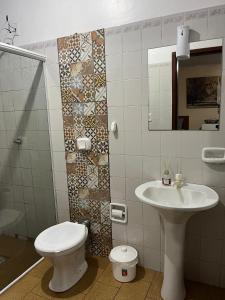 a bathroom with a sink and a toilet and a mirror at Camping e Hostel Internacional in Foz do Iguaçu