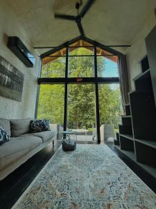 a living room with a couch and a large window at River Nest Tiny House in Iecava