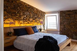 a bedroom with a bed and a stone wall at Stevoski Rooms - Modern Comfort in a Historic Stone House in Cormòns