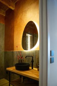 a bathroom with a black sink and a mirror at Stevoski Rooms - Modern Comfort in a Historic Stone House in Cormòns