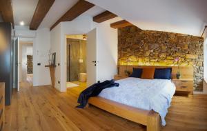 a bedroom with a large bed with a stone wall at Stevoski Rooms - Modern Comfort in a Historic Stone House in Cormòns