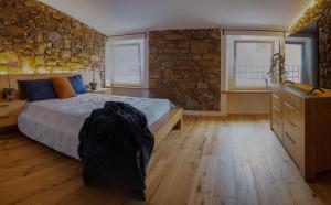a bedroom with a bed and a stone wall at Stevoski Rooms - Modern Comfort in a Historic Stone House in Cormòns +22 photos