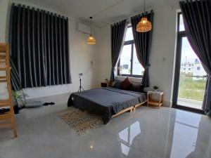 a bedroom with a bed and two large windows at Nhi Homestay Phòng đơn 1 in Rạch Giá