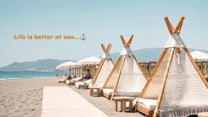 a row of beach chairs and umbrellas on the beach at Apartmani Enydoo in Ulcinj