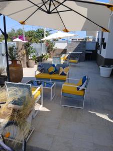 a patio with couches and chairs and an umbrella at B&B villa brezza marina in Sant'Isidoro