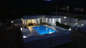 a house with a swimming pool at night at Villa Martar in Mostar +4 photos