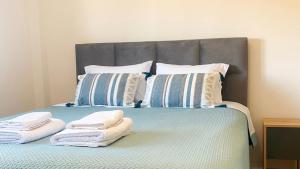 a bed with two pillows and towels on it at Βίλα Αντί Ονείρου-Διαμέρισμα Αριάδνη in Kriezá