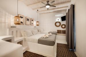 a white bedroom with a bed and pendant lights at Blue Waves Suites & Apartments - To Kyma in Drios