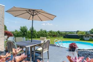 a table with an umbrella next to a pool at Gîte d'Anpa in Ohey