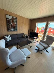 a living room with a couch and two chairs and a television at Finnvika Panorama Corner in Vestvågøya
