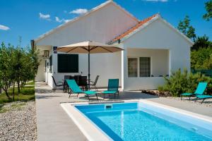 a house with a swimming pool and chairs and an umbrella at Villa Dalmatina in Vedrine