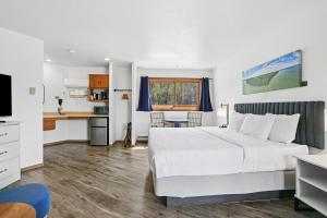 a bedroom with a white bed and a kitchen at Parkside Inn in Ellison Bay