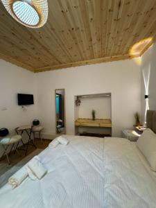 a bedroom with a large white bed with a wooden ceiling at Golden Guest House in Gjirokastër
