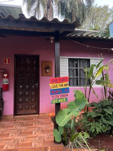 a pink house with a sign in front of it at Camping e Hostel Internacional in Foz do Iguaçu