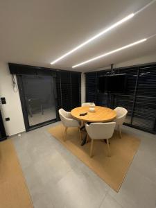 a dining room with a wooden table and white chairs at BK Apartment in Xanthi