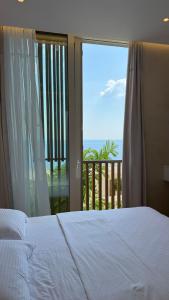 a bedroom with a bed and a view of a balcony at Green Coast Pearl Suites Apartments Palase in Palasë
