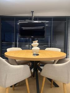 a wooden table with white chairs and a television at BK Apartment in Xanthi