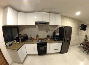 a kitchen with white cabinets and a black refrigerator at Nuevos departamentos en Valle de Bravo in Valle de Bravo