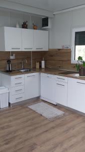 a kitchen with white cabinets and a wooden floor at Resort-Music Mostar in Potoci