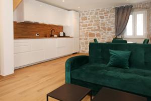 a living room with a green couch and a kitchen at Old town Bol apartments in Bol