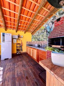 an outdoor kitchen with wooden floors and a white refrigerator at Chácara buriti in Pirenópolis