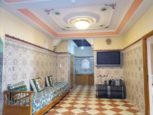 a room with a tiled wall with a couch and a tv at Set in Taza