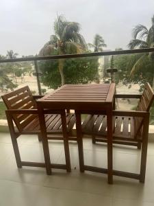 a wooden table and chairs on a balcony with palm trees at Bait Al Marina in Salalah