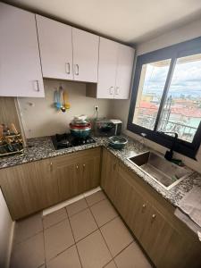a kitchen with white cabinets and a sink and a window at Etienne Gae 2 in Douala