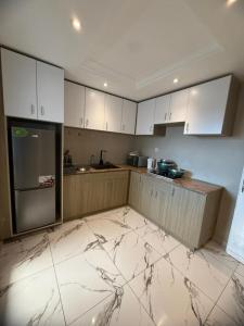 a kitchen with white cabinets and a marble floor at Etienne Gae 2 in Douala +10 photos