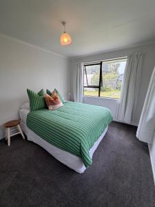 a bedroom with a bed with a green and white blanket at Esplanade Stay in Kaikoura