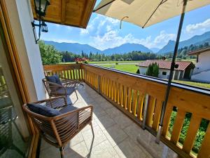 a balcony with chairs and an umbrella and mountains at Apartment Traumblick in Unterammergau