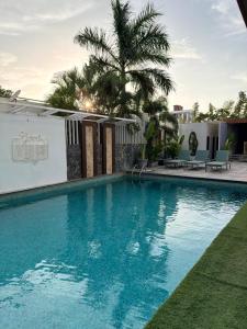a large swimming pool with a palm tree in the background at Nova Bliss Villa in Nashik
