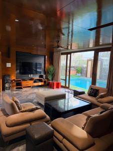 a living room with couches and a tv and a pool at Nova Bliss Villa in Nashik