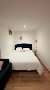 a bedroom with a white bed and a black couch at Sauna spa in Rouen