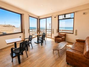 a living room with a couch and tables and windows at Family Surf Chicama in Puerto Chicama
