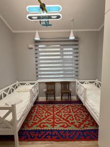 a bedroom with two beds and two chairs and a rug at Ala-Archa Mountain House in Vorontsovskoye