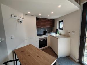 a small white kitchen with a wooden table in it at Mini Condos 2 Studio-Loft with garden in Mrčevac
