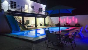 ein Schwimmbecken mit einem Tisch und einem Sonnenschirm in der Unterkunft Hotel Jasli Escárcega in Escárcega