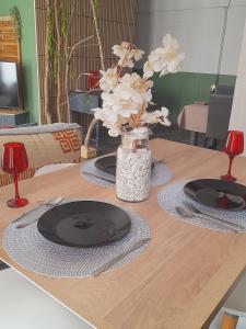 a table with two plates and a vase of flowers at Oasis in Agen