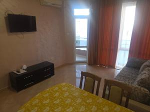 a living room with a table and a couch and a television at Apartments Dani in Pomorie