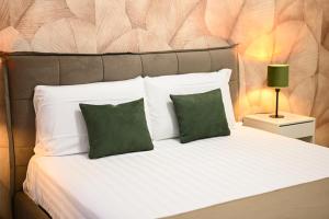 a white bed with two green pillows on it at Victry's Houses Chiaia in Naples