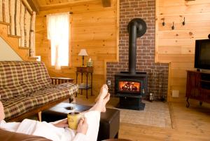 a person sitting in a living room with a fireplace at Natur'Eau Chalets & Spa in Mandeville