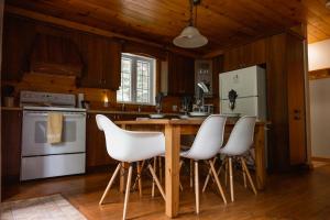 a kitchen with a counter with white chairs in it at Natur'Eau Chalets & Spa in Mandeville