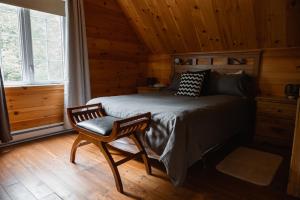 a bedroom with a bed and a chair in a cabin at Natur'Eau Chalets & Spa in Mandeville +53 photos