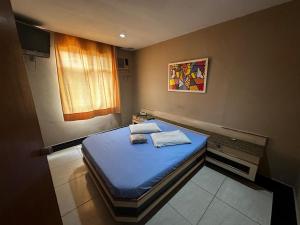 a small bedroom with a blue bed in it at Grande Hotel in Duque de Caxias